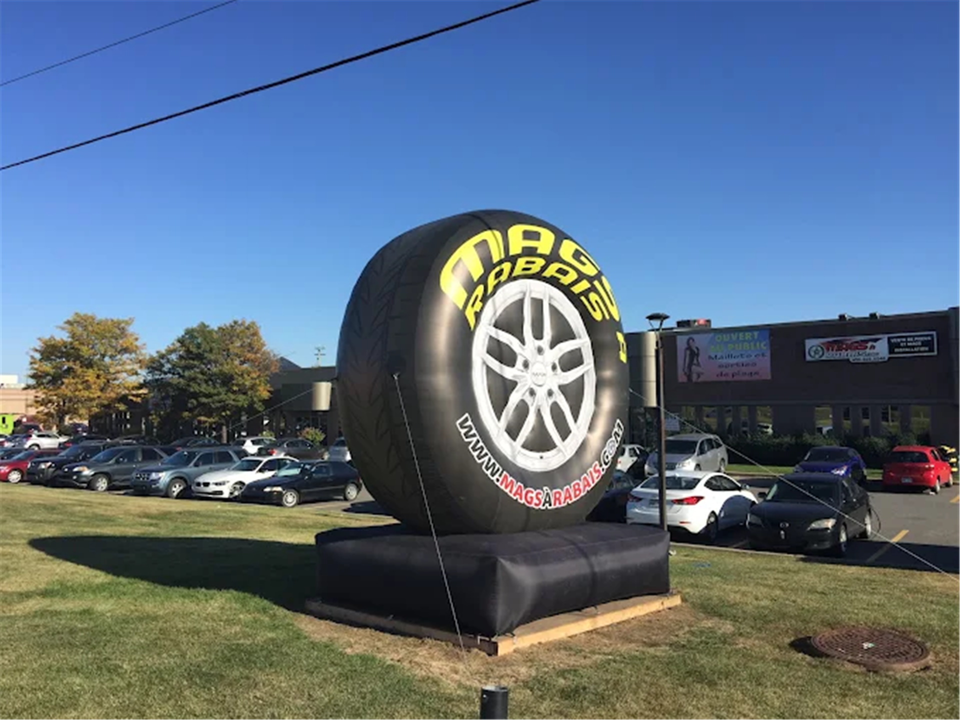 Large %STORENAME% branded inflatable tire displayed outside the store near customer parking.