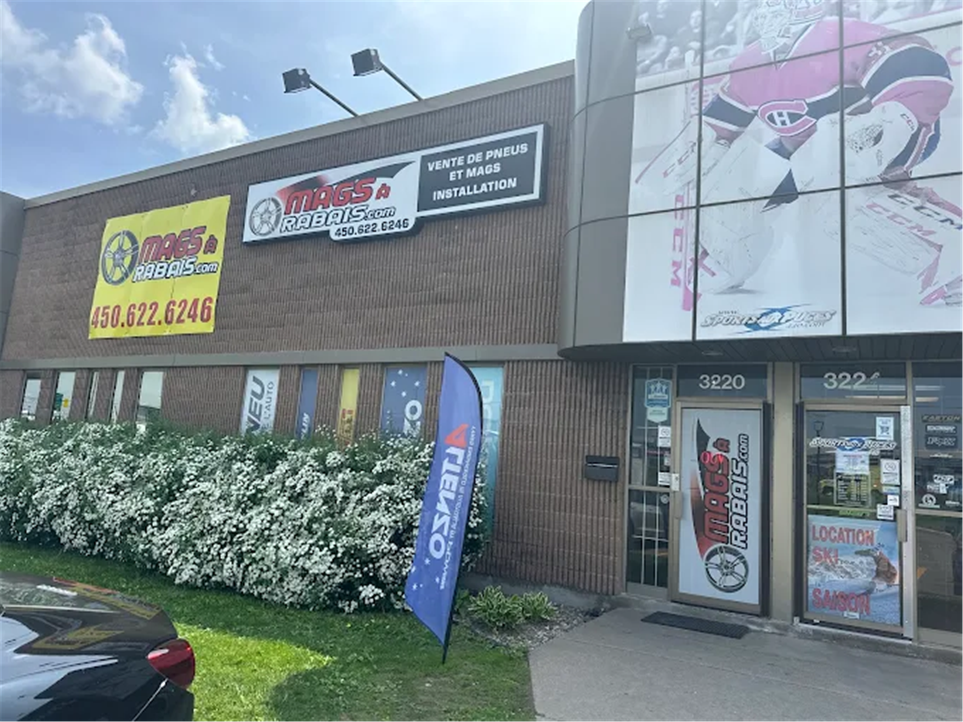 %STORENAME% storefront with exterior signage, entrance doors, window graphics, and branded flags.