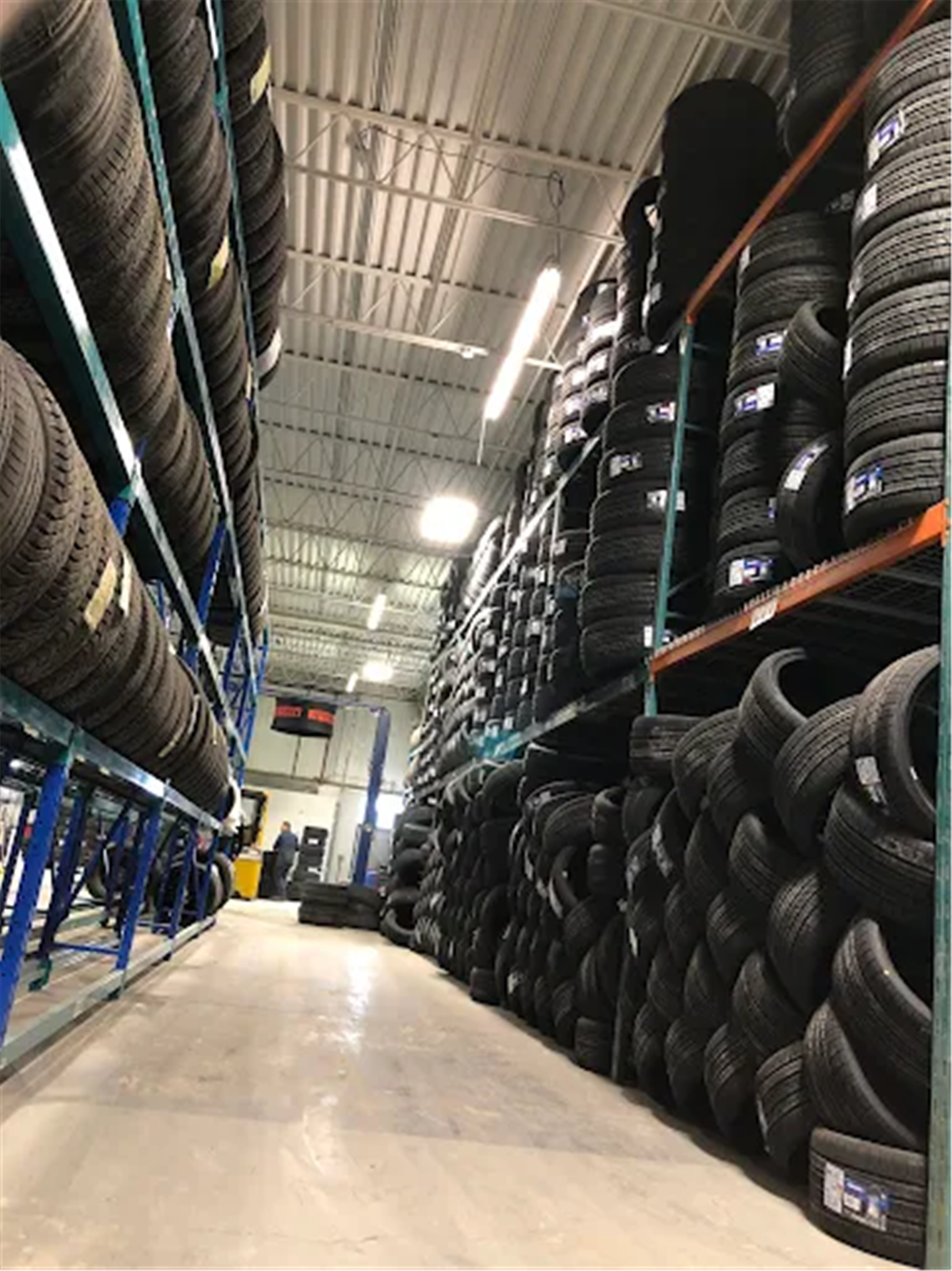 Allee de stock de pneus avec pneus empiles sur rayonnages chez %STORENAME%.