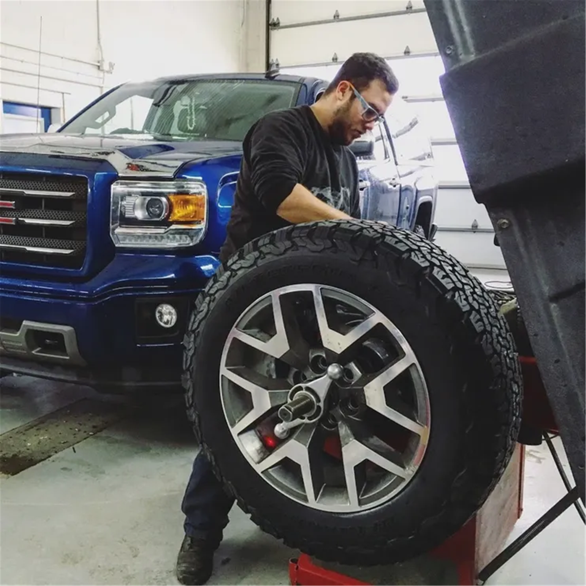 Pneus Benoit Roy employee mounting and balancing replica wheels onto a GMC 