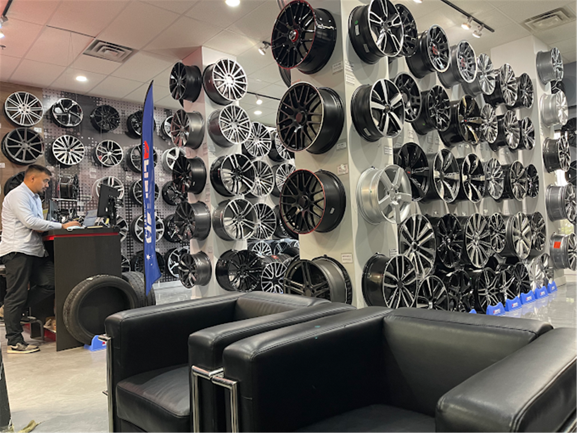 Salle d'exposition %STORENAME% avec mur de roues, comptoir de service et places assises.
