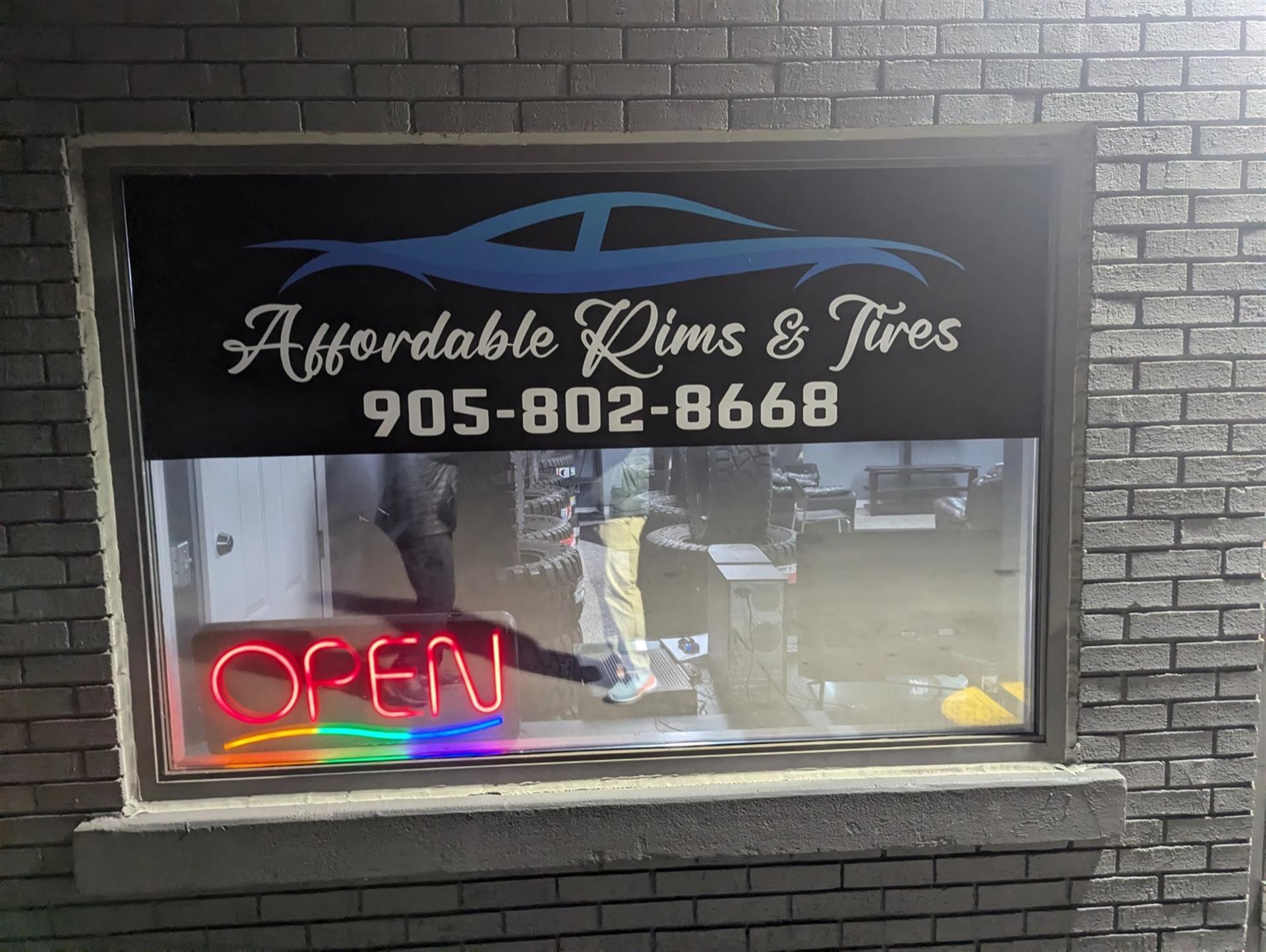 Affordable Rims and Tires storefront window with business sign and open sign.
