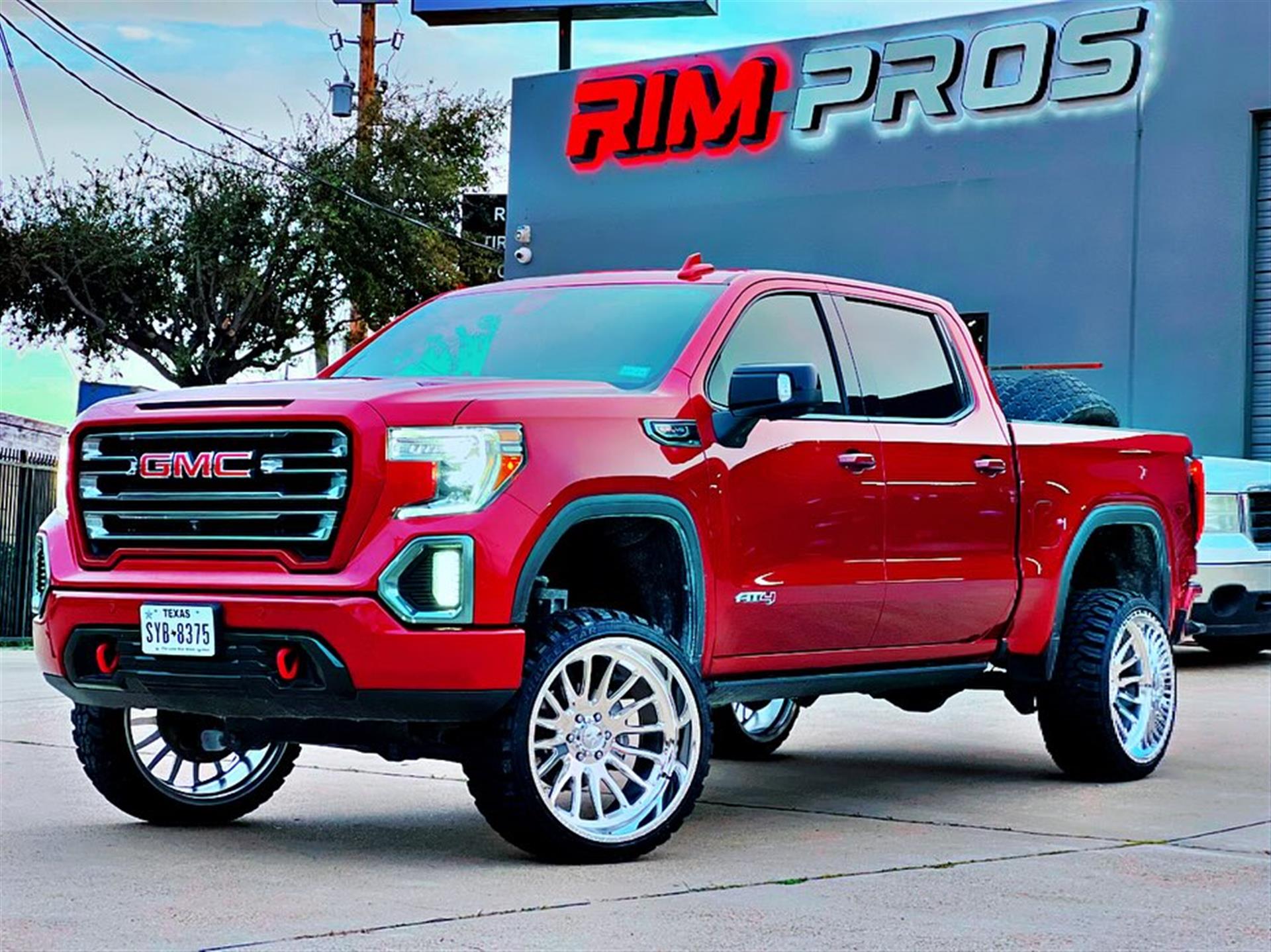 Ford F-250 with a lift and American Force wheels in front of the Rim Pros warehouse